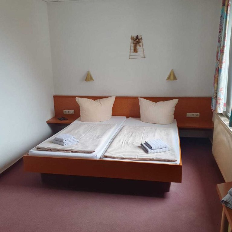 Ein einfaches Hotelzimmer mit Doppelbett, Nachttischen und Teppichboden.